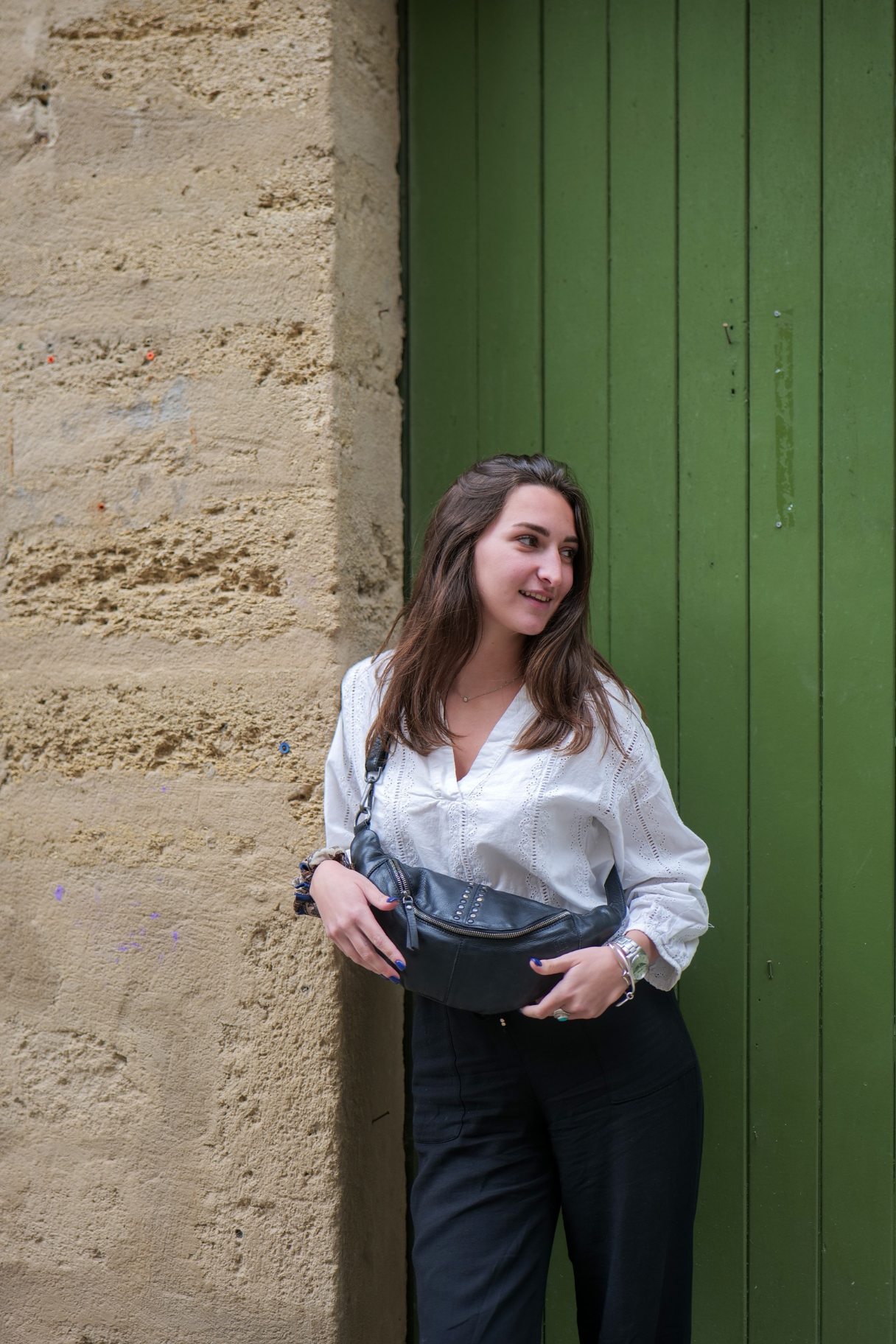 femme portant un sac banane en cuir noir Biba avec clous