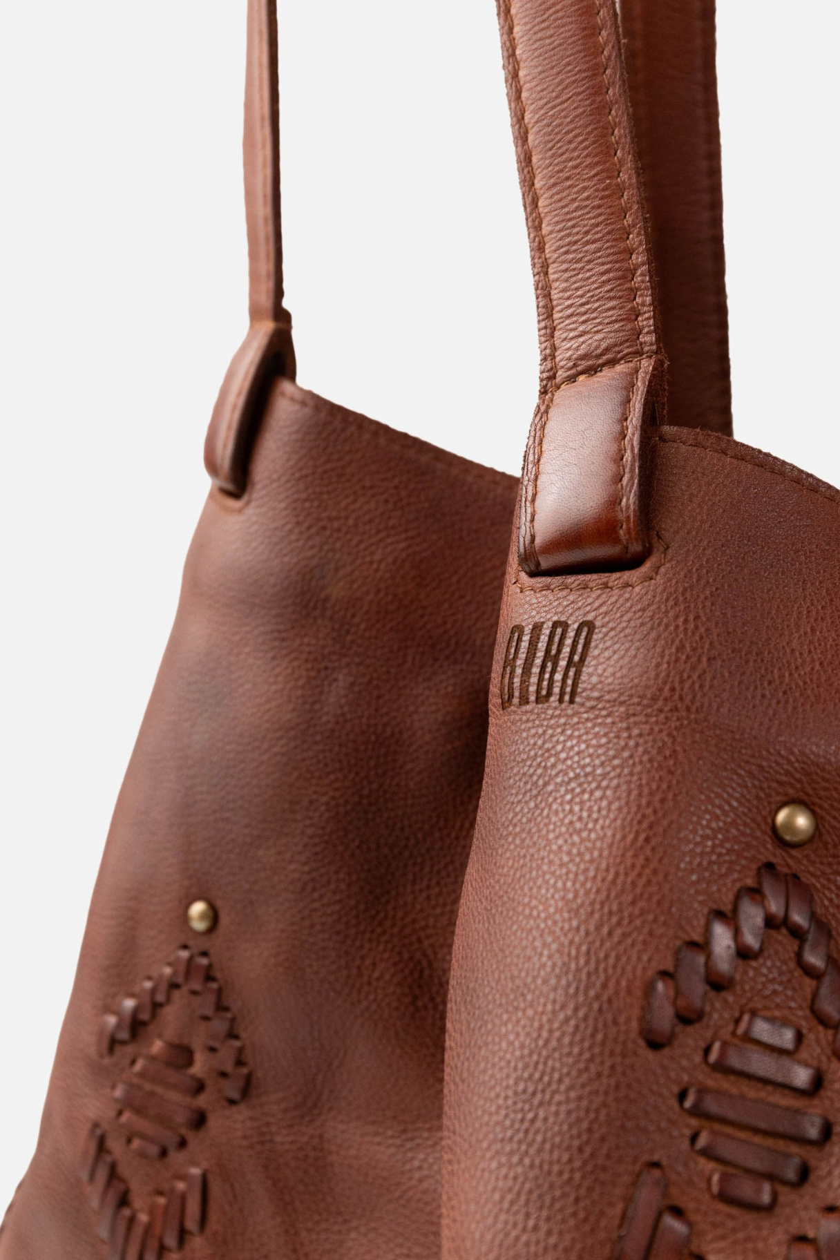 Détail du sac cabas Bayron Biba en cuir cognac : signature gravée, anse cousue main et tissage ethnique