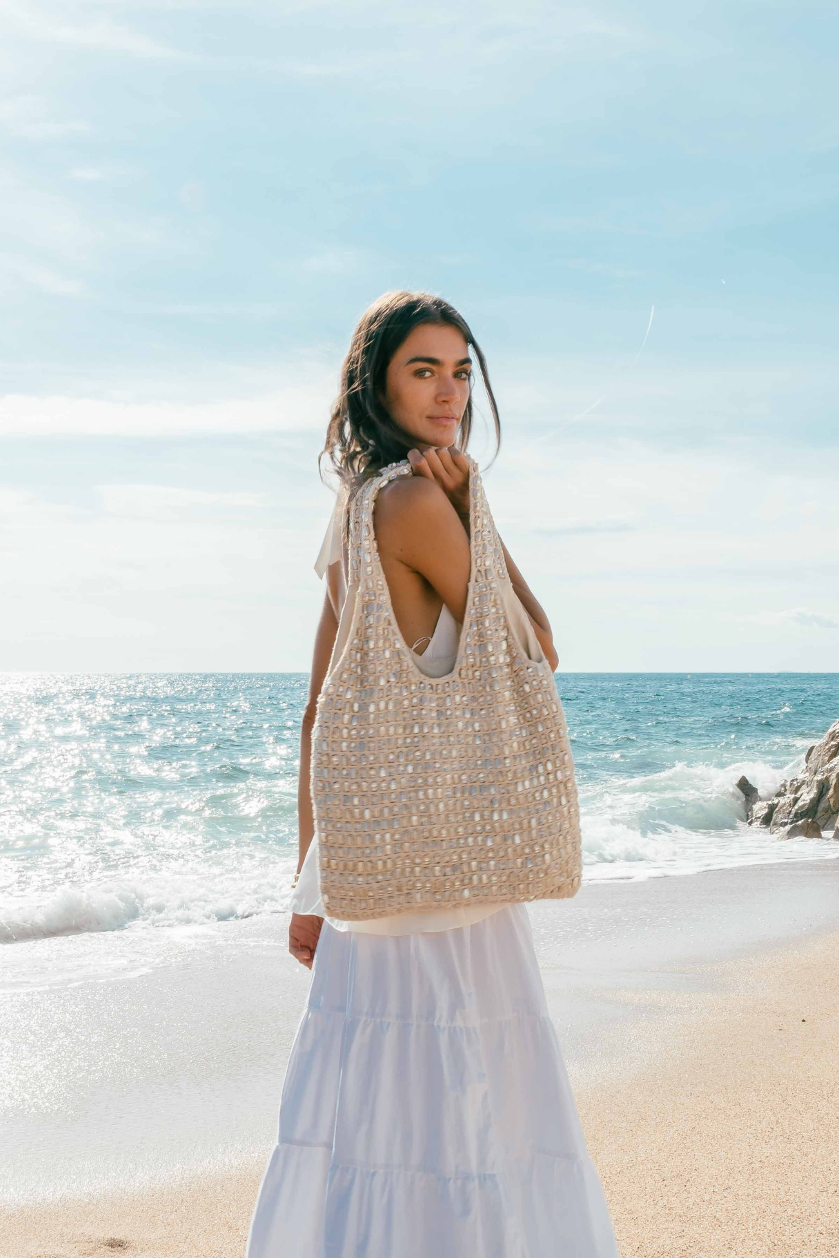 Sac cabas Shell Biba en crochet écru et nacre véritable porté avec une robe longue blanche